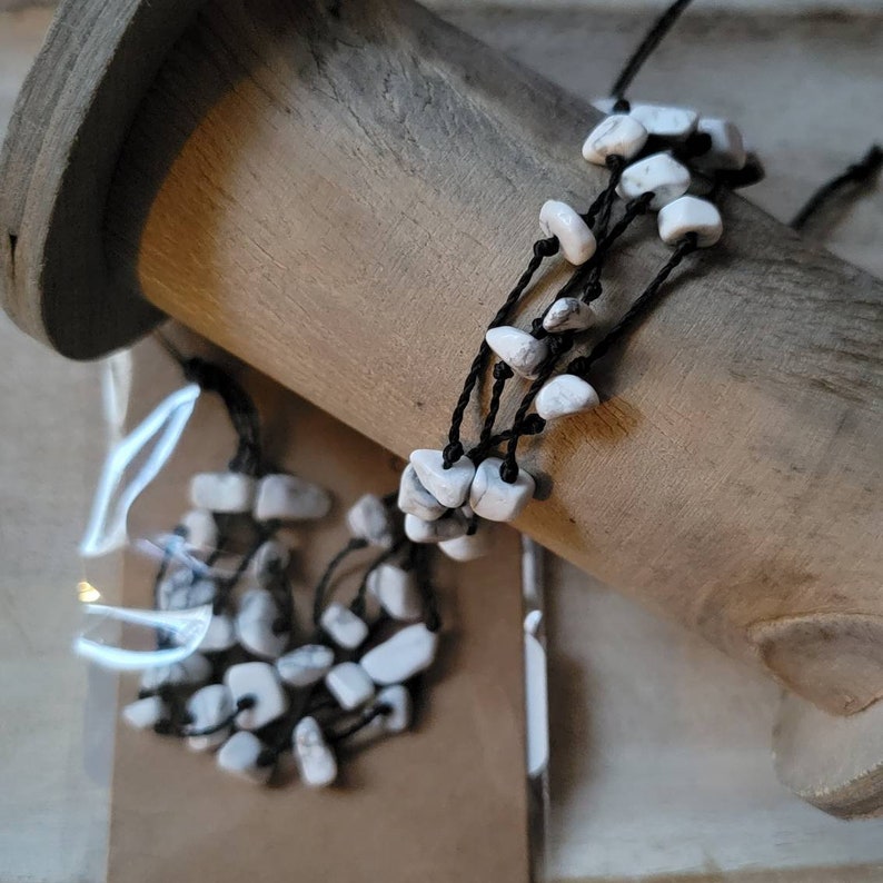 May include: A white howlite stone bracelet with black string. The bracelet is made of multiple strands of string with howlite stones tied to each strand.