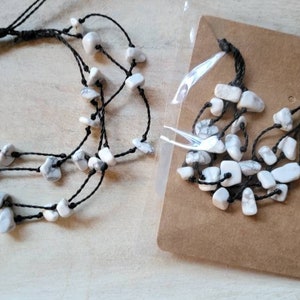 May include: A set of two necklaces with white stone beads and black string. The necklaces are layered and have a simple design.