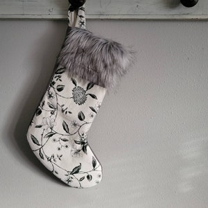 May include: A white Christmas stocking with a black floral pattern and a gray faux fur cuff.