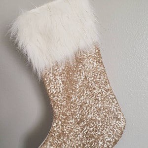 May include: A gold sequin Christmas stocking with a white faux fur cuff.