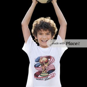 May include: A young person holds a soccer ball overhead, smiling. They wear a white t-shirt with a graphic of the World Cup trophy, the American flag, and the text "World Cup 2026 USA". The background is black.