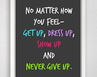 Könnte beinhalten: Ein gerahmter Druck mit weißem Rand und schwarzem Hintergrund. Der Text lautet: "NO MATTER HOW YOU FEEL - GET UP, DRESS UP, SHOW UP AND NEVER GIVE UP." Die Wörter "GET UP", "DRESS UP" und "SHOW UP" sind in Blau, Lila und Pink.