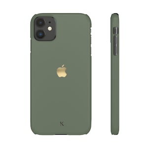 May include: Olive green phone case with a gold Apple logo and a small 'k' at the bottom. The case has a matte finish and a raised edge around the camera. The side view shows the case's buttons and a smooth, rounded edge.