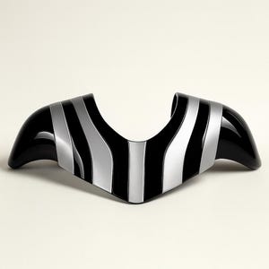 May include: A black and silver decorative object with a curved shape. The object has a glossy black finish with silver stripes. The design is symmetrical, with two flared ends and a central curve.