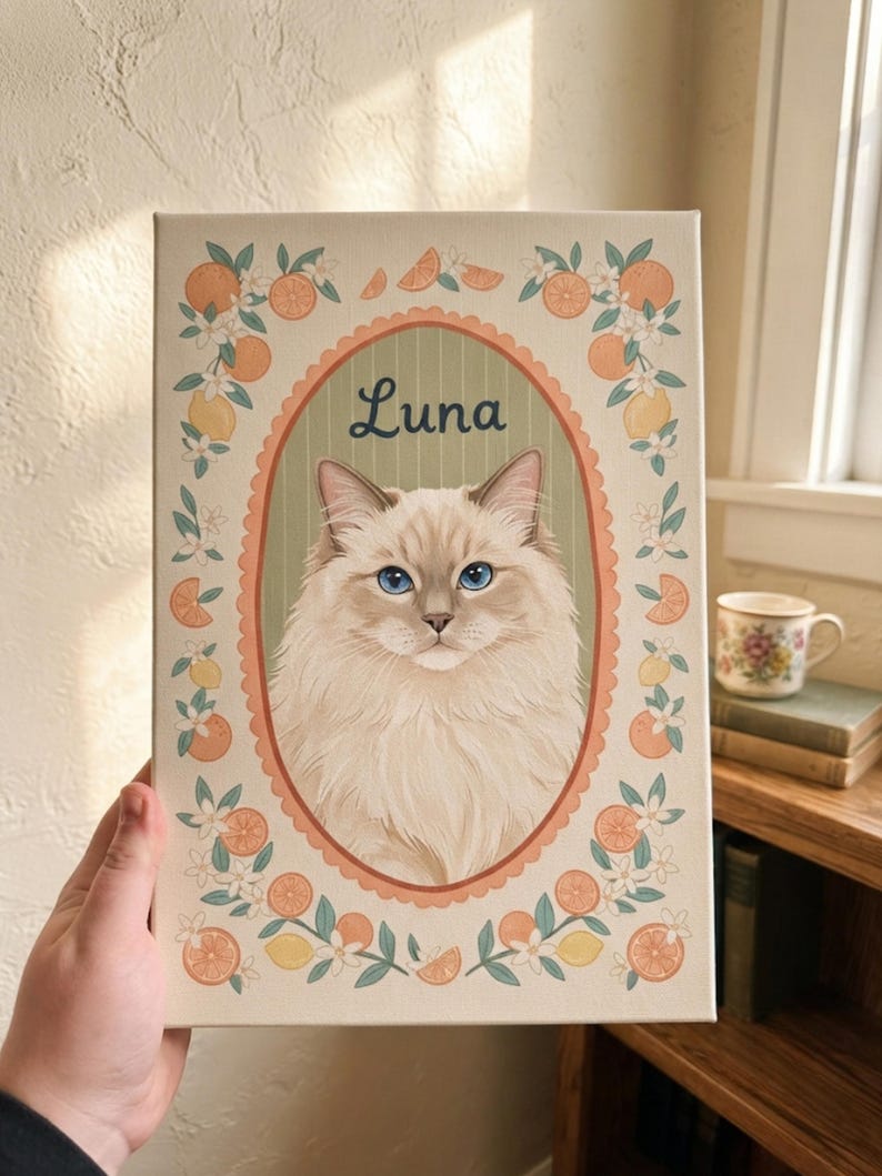 May include: A rectangular canvas print featuring a portrait of a fluffy cream-colored cat with blue eyes inside an oval frame. The name Luna is written above the cat. The border is decorated with illustrations of orange slices and white flowers.