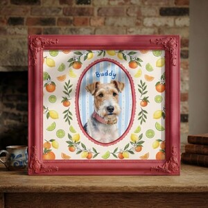 May include: A square red ornate frame containing a portrait of a wire-haired terrier dog wearing a pink collar. The dog is centered in an oval frame against a blue and white striped background with the name Buddy written above the dog's head.