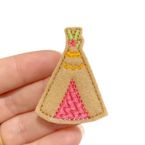 May include: A felt applique of a brown teepee with pink, yellow, and green embroidery. The teepee has a decorative pattern at the top.