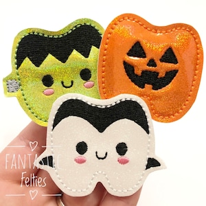May include: Three felt Halloween-themed appliques. A green Frankenstein, an orange pumpkin, and a white vampire tooth.