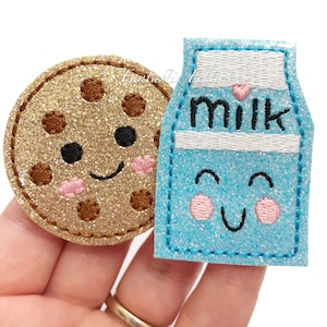 May include: A set of two felt appliques, a gold glitter cookie and a blue glitter milk carton, both with embroidered smiling faces.