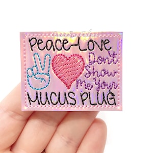 May include: A pink iridescent iron-on patch with a peace sign, a heart, and the text "Peace Love Don't Show Me Your Mucus Plug".