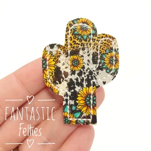 May include: A cactus-shaped felt applique with a sunflower and leopard print design. The applique features yellow sunflowers, a leopard print pattern, and a cowhide print. The text "FANTASTIC Felties" is visible in white script.
