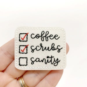 May include: White felt patch with a black embroidered checklist. The checklist has three items: coffee, scrubs, and sanity. The first two items are checked off with red checkmarks. The last item is unchecked.