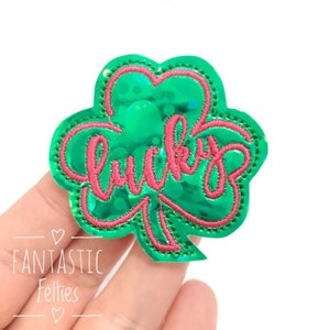 May include: Green shamrock-shaped patch with the word "lucky" embroidered in pink.