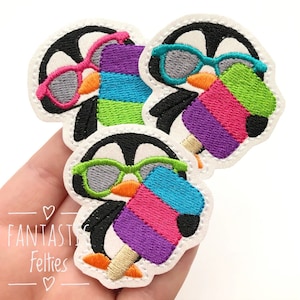 May include: Embroidered patches featuring cartoon penguins wearing sunglasses and holding colorful popsicles. The patches have a white border and the text "Fantastic Felties". The penguins are black and white with orange beaks.