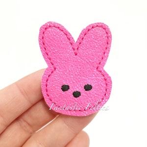 May include: Pink felt bunny applique with black eyes and a nose. The bunny is stitched around the edges.