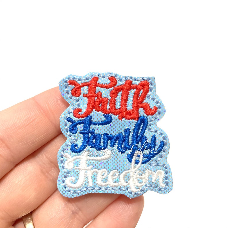 Puede incluir: Un parche de tela azul con las palabras "Faith Family Freedom" bordadas en hilo rojo, azul y blanco.