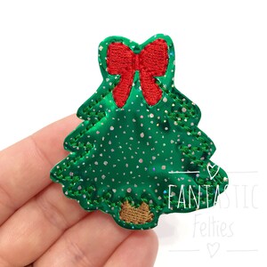 May include: Green glitter Christmas tree with a red bow on top. The tree has a brown felt base. The text "Fantastic Felties" is written below the tree.