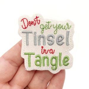 May include: White felt applique with red, green, and silver embroidery. The text reads "Don't get your Tinsel in a Tangle".