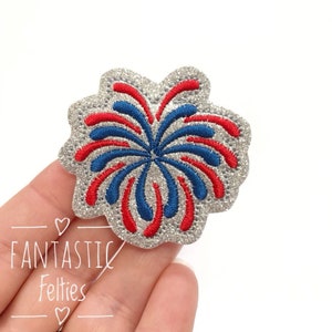 May include: A silver glitter iron-on patch with a red, white, and blue firework design.