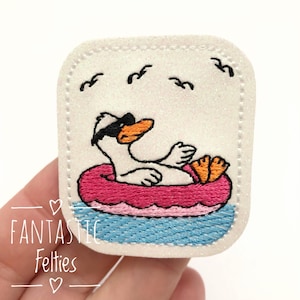 May include: Embroidered patch featuring a cartoon duck wearing sunglasses and relaxing in a pink inflatable ring. The duck is on a blue water background with birds flying above. The patch has a white glittery background and a stitched border.