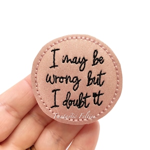 May include: A round, blush-colored felt patch with the embroidered phrase, "I may be wrong but I doubt it" in black script. The patch has a stitched border and the text "Fantastic Felties" is at the bottom.
