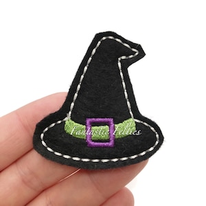 May include: A black felt witch hat with a green belt and purple buckle, outlined with white stitching. The hat has the text "Fantastic Felties" on the front. This Halloween-themed item is perfect for crafting or embellishing.