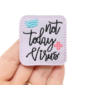 May include: A purple square patch with white stitching around the edges. The patch has a pink embroidered flower, a blue embroidered face mask, and black embroidered text that reads "not today virus". The text "Fantastic Felties" is also embroidered in black at the bottom of the patch.