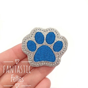 May include: A blue paw print embroidered on a silver glitter felt patch.