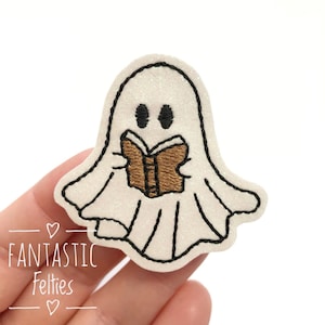 May include: A white glitter ghost with black eyes and a black outline is reading a brown book. The ghost is holding the book with its hands.