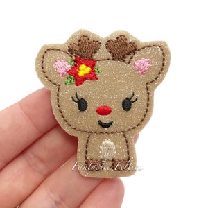 May include: A brown glitter reindeer applique with a red poinsettia flower, pink ears, and black eyes. The reindeer has a brown nose and a white belly. The applique is perfect for adding a festive touch to crafts and projects.