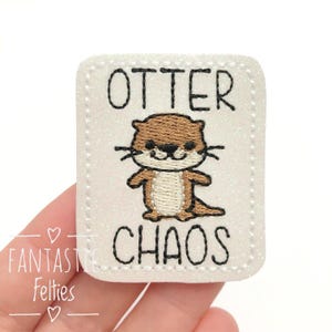 May include: White felt patch with a brown and white embroidered otter and the text "Otter Chaos".