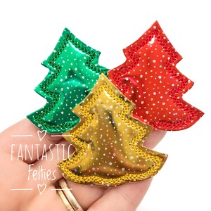 May include: Three felt Christmas tree ornaments in green, gold, and red with glitter accents.  The ornaments are in the shape of a traditional Christmas tree.