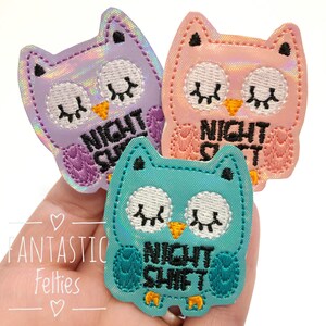 May include: Three iridescent owl felt patches with the text "Night Shift" embroidered on each. The owls are in purple, pink, and teal.