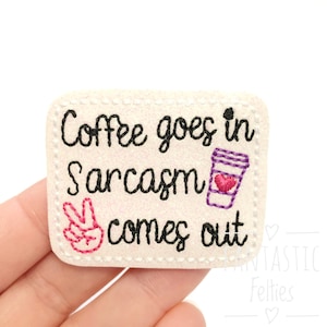May include: White felt patch with black embroidery that reads "Coffee goes in Sarcasm comes out". A pink peace sign and a purple coffee cup with a pink heart are also embroidered on the patch.