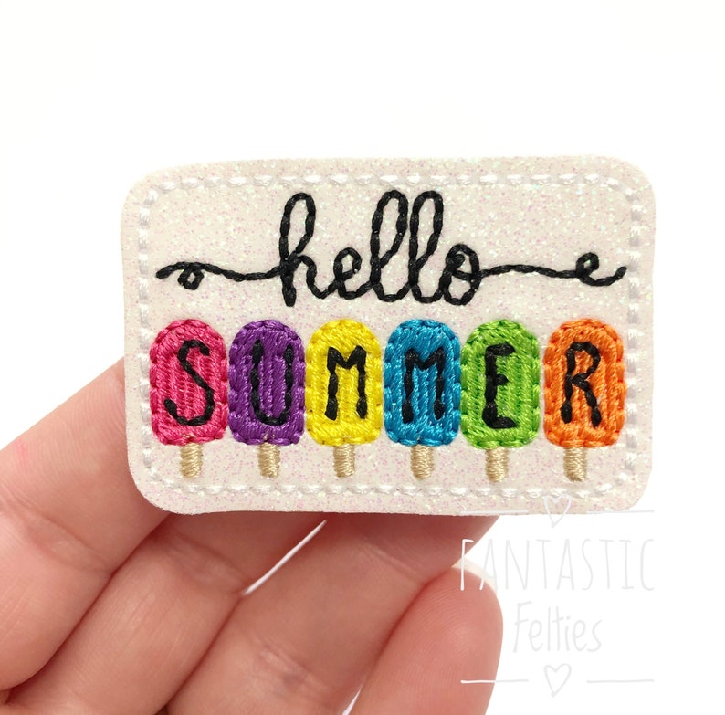 May include: A white felt patch with the words "hello summer" in black cursive script. The word "summer" is spelled out with colourful popsicle-shaped letters.