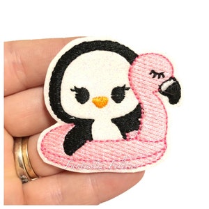 May include: A white penguin with black eyes and a black beak is floating on a pink flamingo pool float. The penguin has eyelashes and a small orange beak.