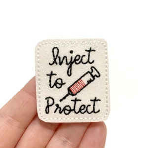 May include: White felt patch with black stitching and the text "Inject to Protect" with a red and white syringe graphic.