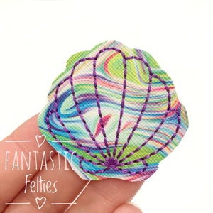 May include: A purple and green seashell with a marbled pattern. The seashell is made of felt and has a stitched outline.