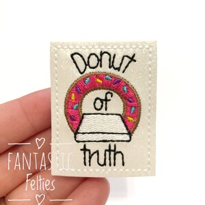 May include: White felt patch with embroidered text "Donut of truth" and a pink donut with sprinkles.