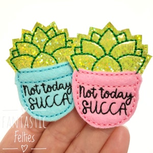 May include: Two felt succulent plant patches with the text "Not today, succa" in black. One patch is light blue and the other is pink.