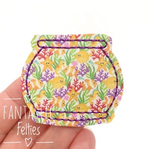May include: A felt fishbowl applique with a purple stitched border. The fishbowl is filled with a colorful pattern of fish, starfish, and coral.