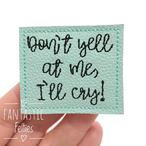 May include: A light blue felt patch with black embroidered text that reads "Don't yell at me, I'll cry!"