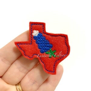 May include: Red felt Texas state outline with blue and white embroidered bluebonnet flower. The felt patch has a blue stitched border and the text "Fantastic Felties" is embroidered in green.