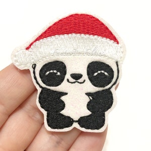 May include: A white and black panda wearing a red and white Santa hat. The panda has a smiling face and is holding its arms up. The text "Fantastic Felties" is on the image.