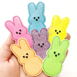 May include: Six felt Easter bunny shapes in various colors, including pink, blue, yellow, green, and purple. Each bunny has a stitched outline and black eyes.