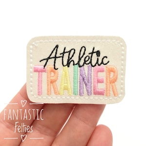 May include: White felt patch with rainbow colored embroidery that reads "Athletic Trainer".