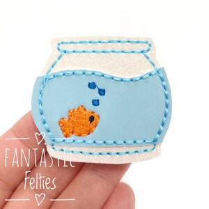May include: A blue felt fishbowl with a glittery surface and a single orange felt fish inside. The fishbowl has a blue felt rim and a white felt base.