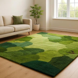 Puede incluir: Una alfombra rectangular verde con un diseño abstracto de formas superpuestas en diferentes tonos de verde. La alfombra está sobre un suelo de madera en un salón, con un sofá beige y una ventana en el fondo. Dimensiones aproximadas: 200 cm x 300 cm.