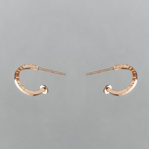 Peut inclure: Une paire de boucles d'oreilles créoles en or rose. Les boucles d'oreilles sont simples et délicates, avec une texture martelée.