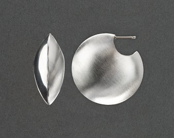 May include: A pair of silver earrings, one is a rounded disc shape and the other is a teardrop shape.